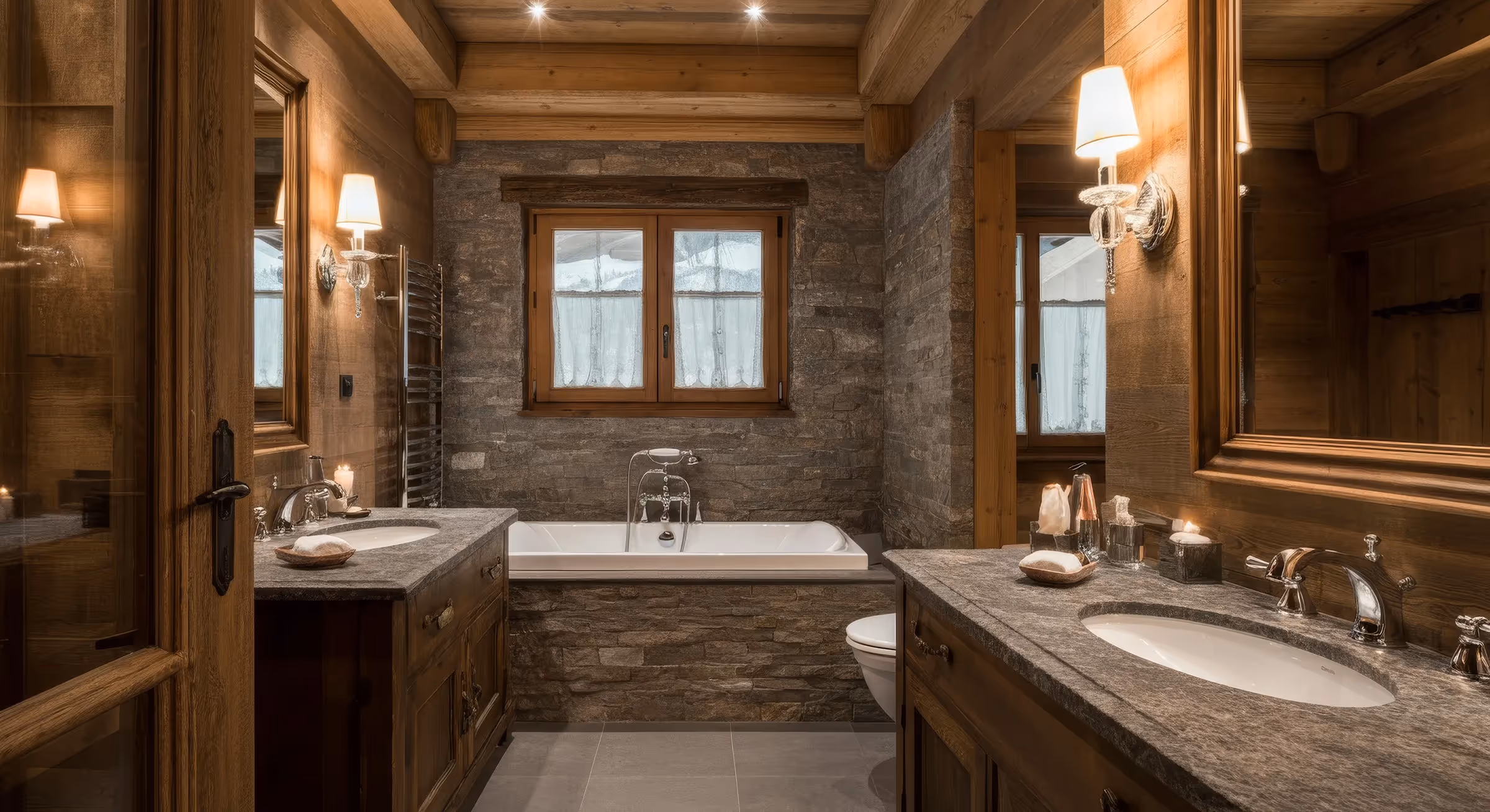 Cozy rustic bathroom with stone walls, wooden accents, a bathtub under a window, and double sinks with granite countertops.